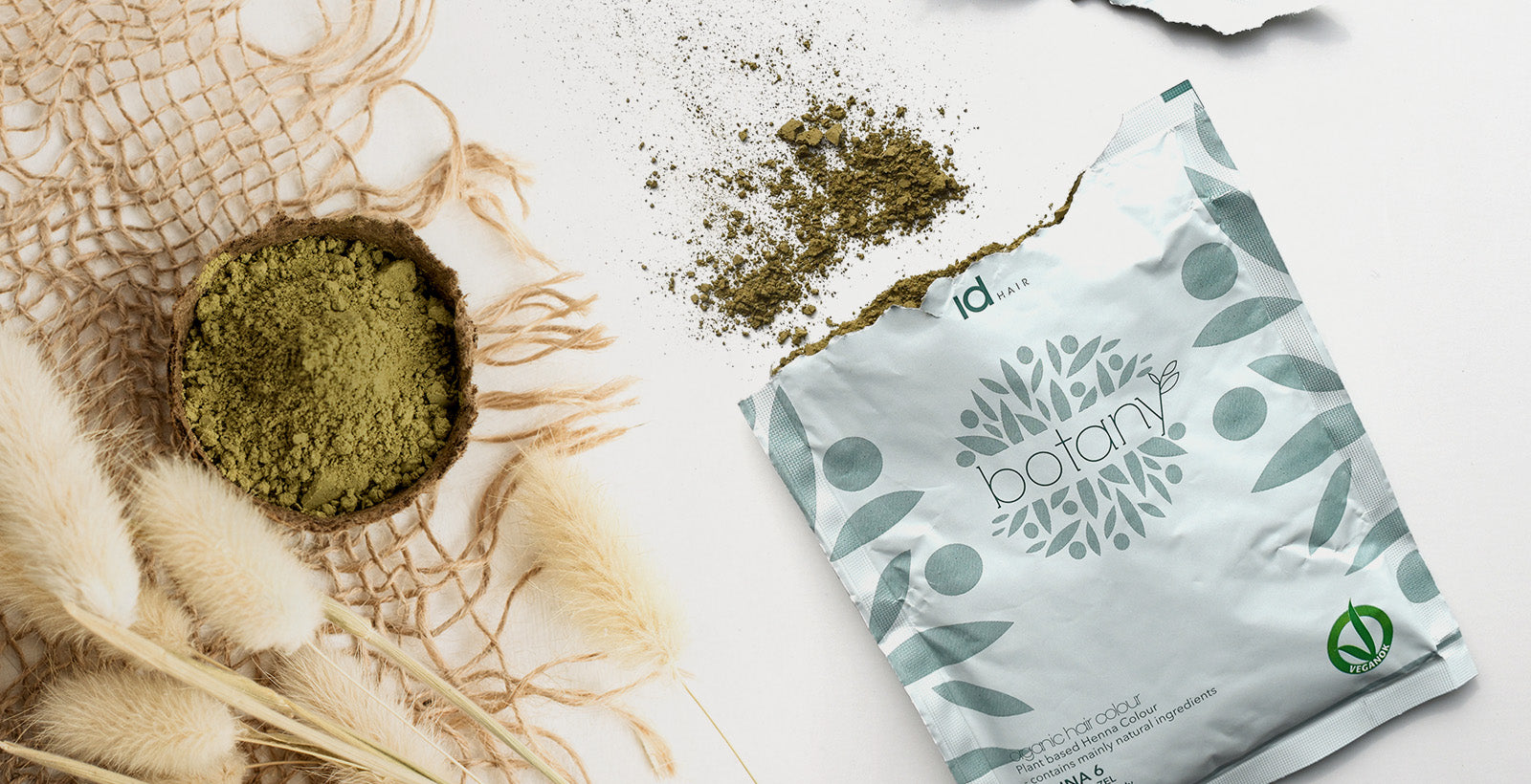 IdHAIR Botany hårfarvepulver og emballage vist med spildt grønt pulver.