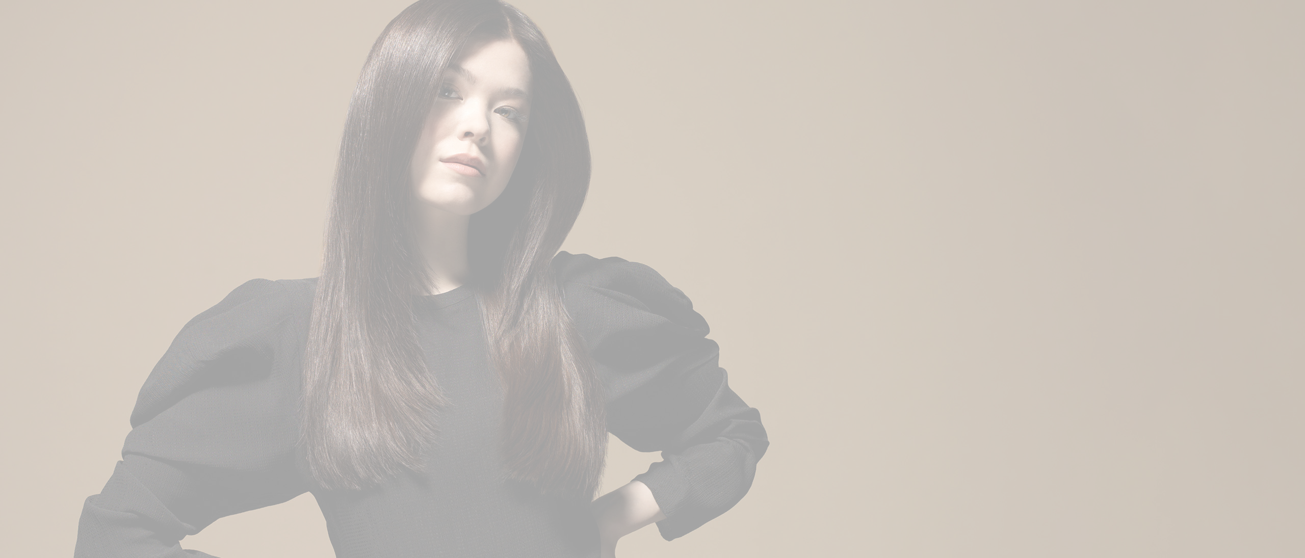 Kvinde med mørkebrunt, glansfuldt hår og midterskilning mod lys beige baggrund