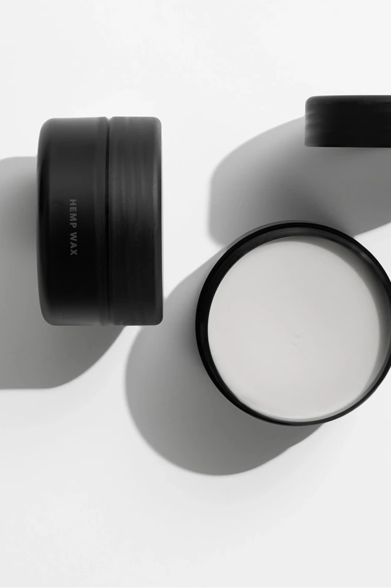 Kreativt opstillet produktbillede af to Hemp Wax fra Black Xclusive. Vokskrukker set oppefra og holdt i sort / hvid. 