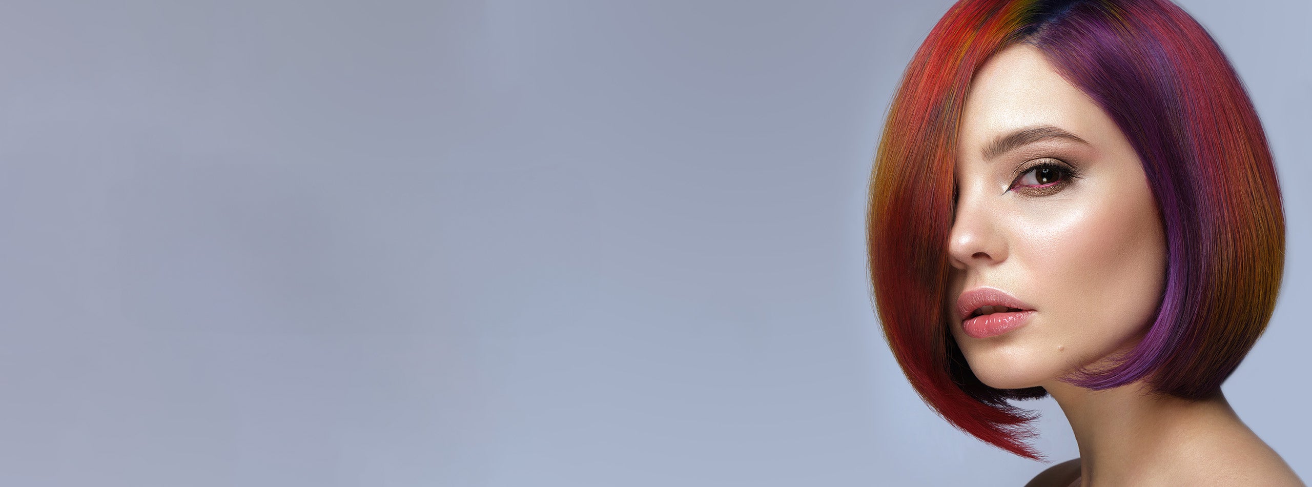 Kvinde med kort, glansfuldt pagehår i rød, orange og lilla farve.