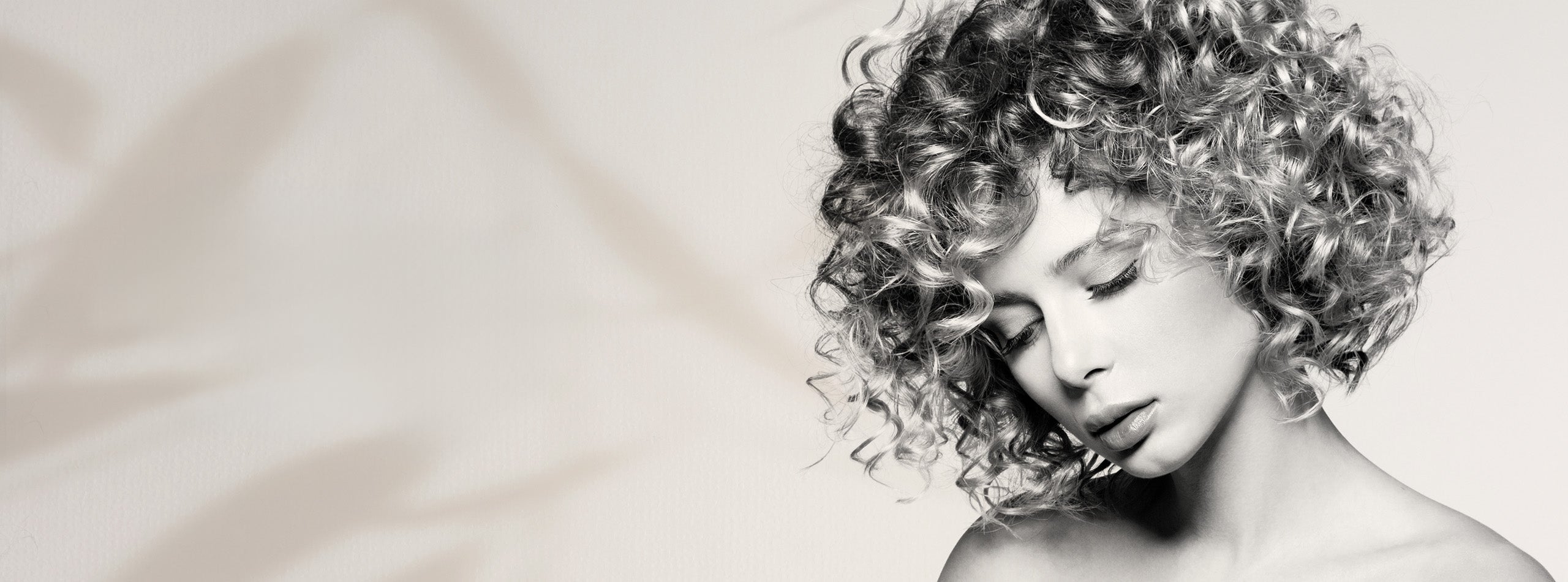 Kvinde med kort, defineret og glansfuldt krøllet hår i sort-hvid stil.