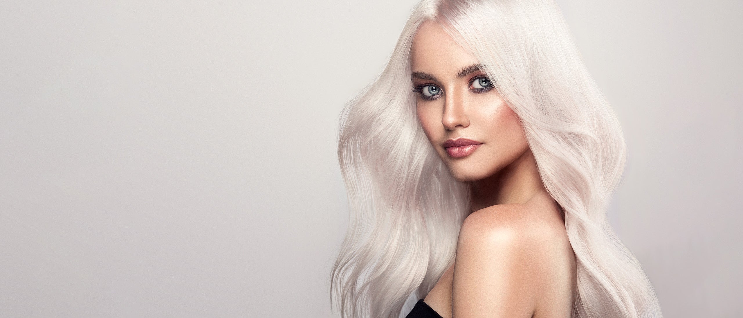 Kvinde med platinblond hårfarve og bløde længder mod lys baggrund.